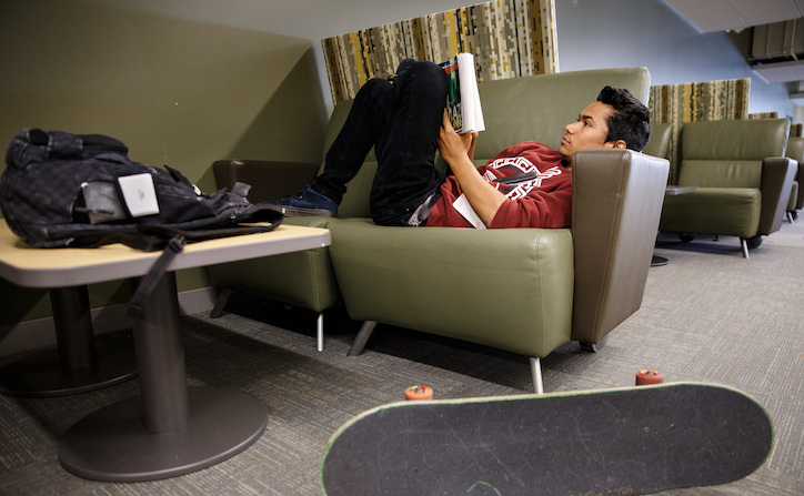 Student lounging and reading a book
