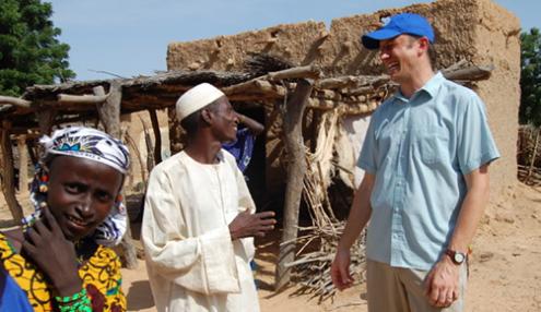Scott in East Africa speaking with two people in the village