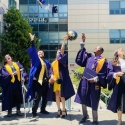 Graduates in cap and gown throwing their hats in the air